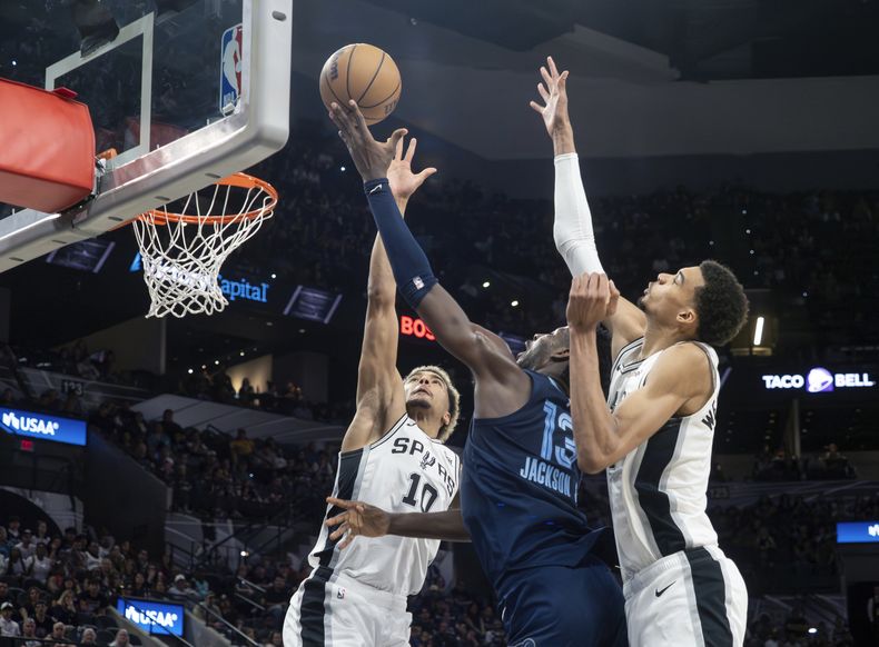 El alero de los Grizzlies de Memphis, Jaren Jackson, Jr., centro, dispara entre los aleros de los Spurs de San Antonio, Jeremy Sochan, a la izquierda, y Victor Wembanyama, a la derecha, durante la segunda mitad de un partido de baloncesto de la NBA, el viernes 22 de marzo de 2024, en San Antonio. (AP Foto/Michael Thomas)