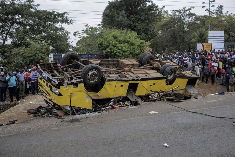 Civiles se reúnen en el lugar donde se volcó un autobús y causó la muerte de varias personas en Kisumu, Kenia, el viernes 8 de agosto de 2025. (AP Foto/Brian Ongoro)