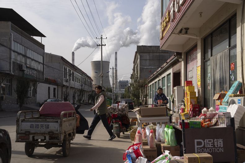 En esta imagen de archivo, la central eléctrica de Guohua, que funciona con carbón, en pleno funcionamiento mientras varios vendedores trabajan en la calle en Dingzhou, Baoding, en la provincia de Hebei, en el norte de China, el 10 de noviembre de 2023. (AP Foto/Ng Han Guan, archivo)