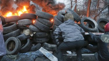 americateve | Actistas tratan de localizar a un francotirador resguard&aacute;ndose en una barricada hecha con llantas viejas cerna de la plaza Independencia de Kiev, capital de Ucrania el jueves 20 de febrero de 2014. (Foto de AP/Efrem Lukatsky)