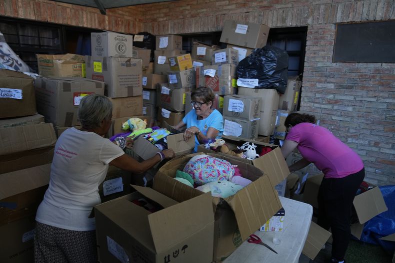 Tres voluntarias organizan cajas con juguetes usados en la organización sin fines de lucro Hospital de los Peluches, en donde recuperan y reparan juguetes usados para donarlos a niños vulnerables como regalos de Navidad, en Caracas, Venezuela, el jueves 5 de diciembre de 2024. (AP Foto/Ariana Cubillos)