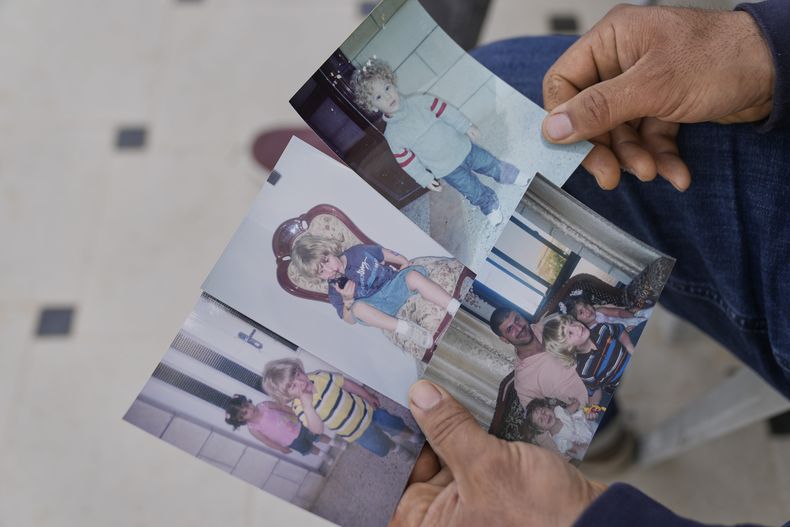 Khalid Ahmad sostiene imágenes de la infancia de su hijo, Waleed, en la casa de su familia en la localidad cisjordana de Silwad, al nordeste de Ramala, el miércoles 26 de marzo de 2025. (AP Foto/Nasser Nasser)