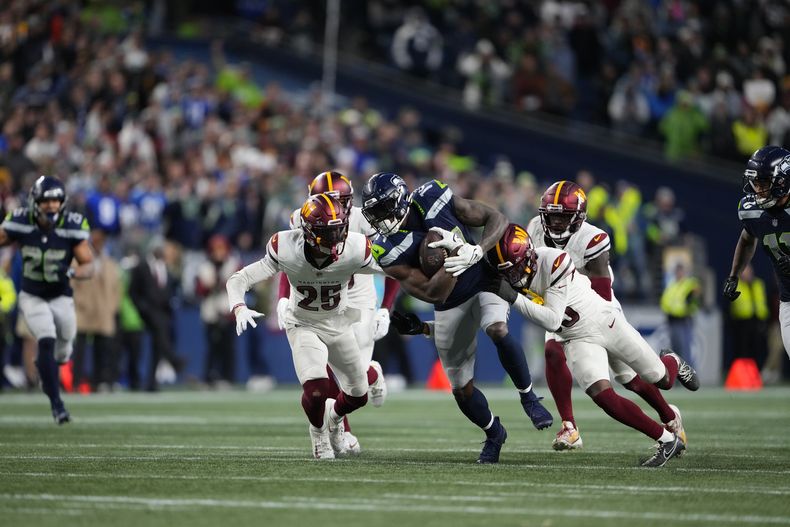 DK Metcalf (14), de los Seahawks de Seattle, se escapa de un par de defensivos de los Commanders de Washington en la segunda mitad del partido de la NFL, el domingo 12 de 2023, en Seattle de 2023. (AP Foto/Lindsey Wasson)