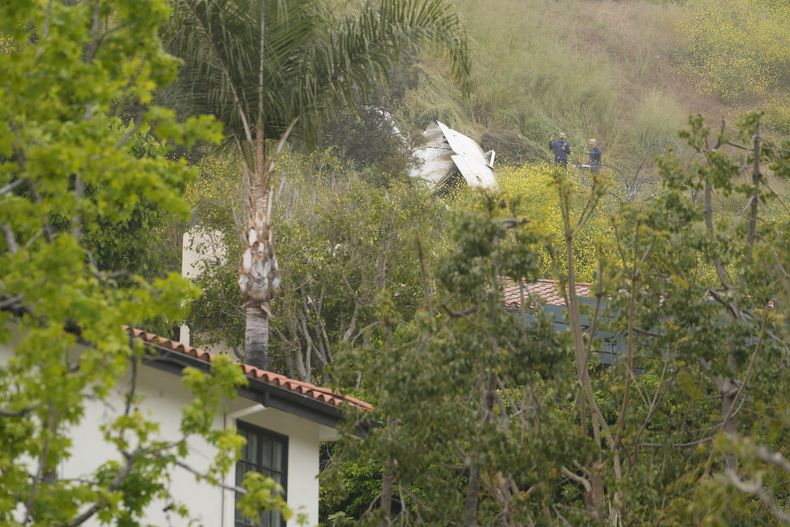 Investigadores de la Junta Nacional de Seguridad en el Transporte inspeccionan una avioneta que cayó sobre una colina, cerca de una casa, en Beverly Glen Circle, el domingo 30 de abril de 2023, en Los Ángeles. (AP Foto/Damian Dovarganes)