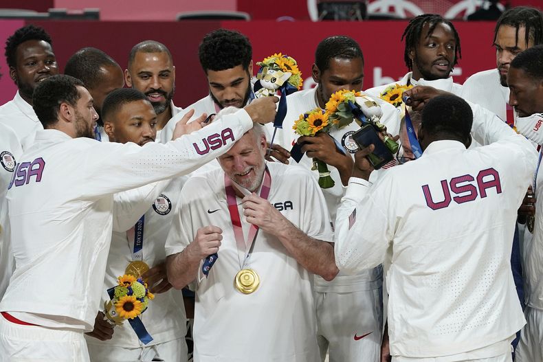 ARCHIVO - Foto del sábado 7 de agosto del 2021, jugadores de la selección de Estados Unidos le colocan la medalla de oro al entrenador Greg Popovich durante la ceremonia de preseas en los Juegos Olímpicos de Tokio. (AP Foto/Charlie Neibergall, Archivo)