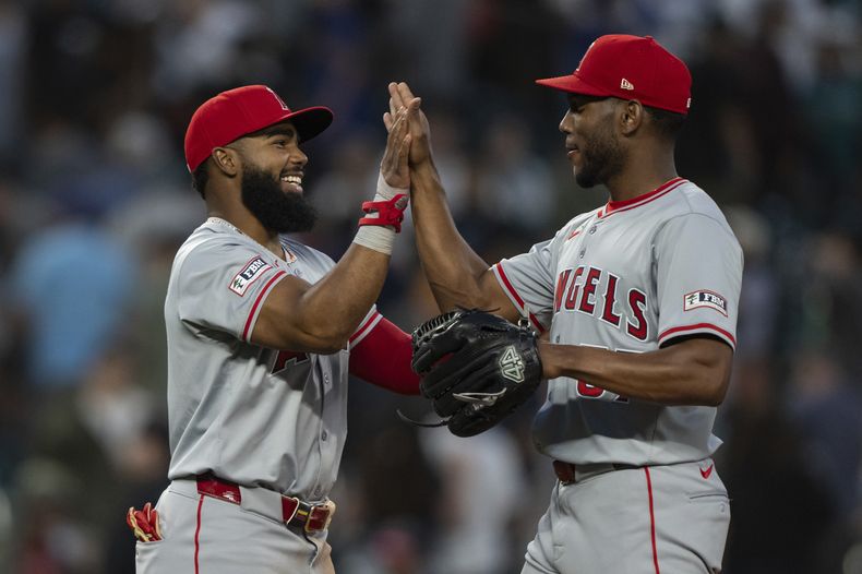 El venezolano Luis Rengifo, de Los Ángeles de los Ángeles (izquierda), y el dominicano Roansy Contreras celebran luego de enfrentarse a los Marineros de Seattle, el martes 23 de julio 2024, en Seattle. (AP Foto/Stephen Brashear)