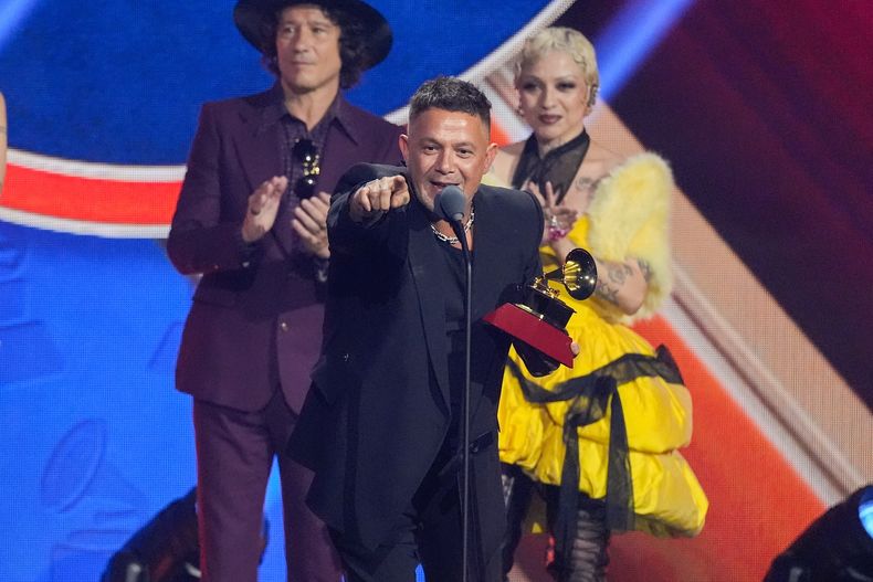 Alejandro Sanz recibe el premio a la grabación del año por Palmeras en el jardín durante la ceremonia de los Latin Grammy 2025, el jueves 13 de noviembre de 2025, en el MGM Grand de Las Vegas. Observan desde la izquierda, en primer plano, los presentadores Enrique Bunbury y Mon Laferte. (Foto AP/Chris Pizzello)