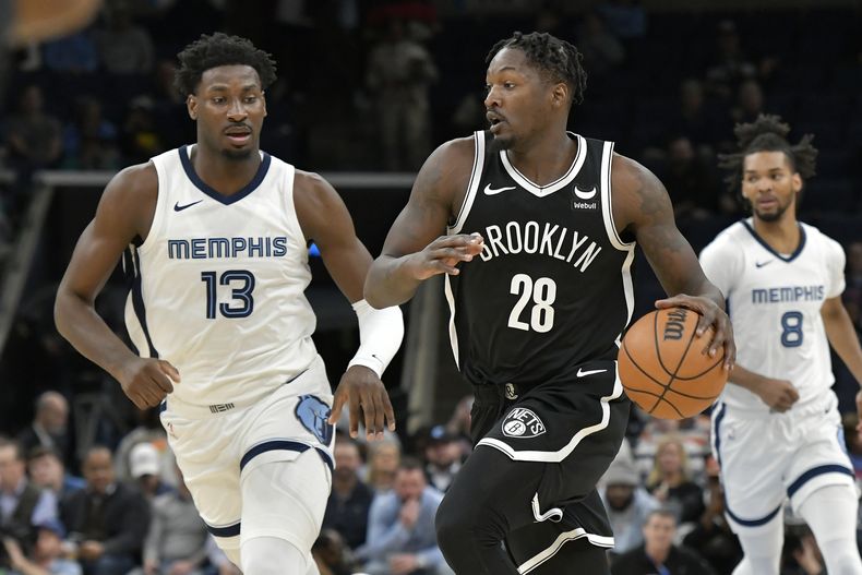 Dorian Finney-Smith (28), de los Nets de Brooklyn, maneja el balón por delante de Jaren Jackson Jr. (13), de los Grizzlies de Memphis, durante la primera mitad del juego de baloncesto de la NBA, el lunes 26 de febrero de 2024, en Memphis, Tennessee. (AP Foto/Brandon Dill)