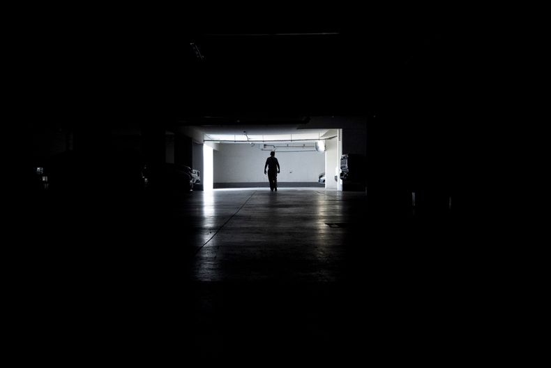 Un hombre camina por un garaje durante un apagón masivo, en Santiago, Chile, el martes 25 de febrero de 2025. (AP Foto/Matías Basualdo)