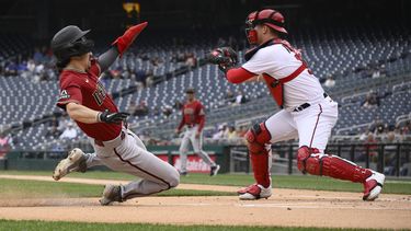 Corbin Carroll de los Diamondbacks de Arizona anota una carrera ante el receptor Riley Adams de los Nacionales de Washington, el jueves 22 de junio de 2023. (AP Foto/Nick Wass)