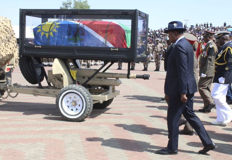 Dolientes siguen el ataúd envuelto en una bandera del fallecido presidente de Namibia, Hage Geingob, durante su funeral en Windhoek, Namibia, el domingo 25 de febrero de 2023. (AP Foto/Esther Mbathera)