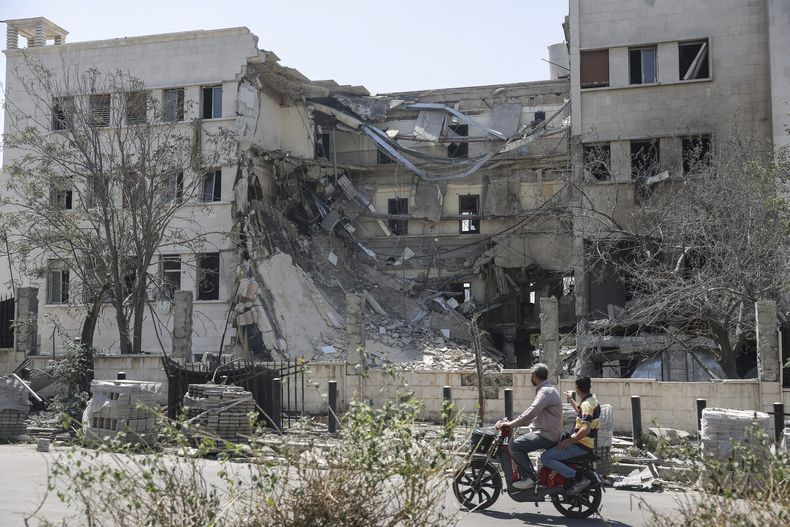Gente pasa ante el edificio del Ministerio sirio de Defensa, que sufrió graves daños el miércoles por ataques aéreos israelíes en Damasco, Siria, el 17 de julio de 2025. (AP Foto/Ghaith Alsayed)