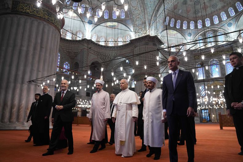El papa León XIV, al centro, caminando con el muecín de la mezquita Asgın Tunca, a la izquierda; el muftí provincial de Estambul, Emrullah Tuncel, segundo desde la izquierda; el imán de la mezquita Sultanahmet Fatih Kaya, y el ministro turco de Cultura y Turismo, Mehmet Nuri Ersoy, visitan la Mezquita Azul en Estambul, el sábado 29 de noviembre de 2025. (Foto AP/Domenico Stinellis)