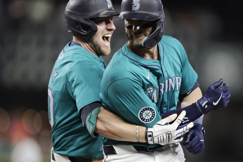 Mitch Haniger de los Marineros de Seattle es abrazado por Luke Raley tras su boleto para la victoria 6-5 en la décima entrada ante los Filis de Filadelfia el sábado 3 de agosto del 2024. (AP Foto/John Froschauer)