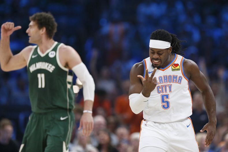 Luguentz Dort, del Thunder de Oklahoma City, festeja un triple junto a Brook López, de los Bucks de Milwaukee, en el encuentro del viernes 12 de abril de 2024 (AP Foto/Nate Billings)