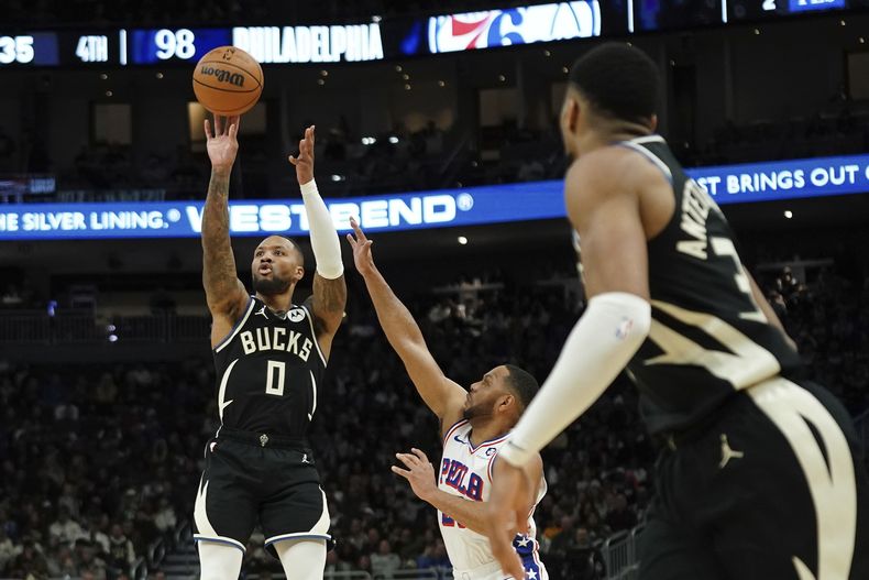 Damian Lillard (0), de los Bucks de Milwaukee, dispara a la canasta mientras Eric Gordon, centro, de los 76ers de Filadelfia, hace un intento por defender, durante la segunda mitad del juego de baloncesto de la NBA, el domingo 9 de enero de 2025, en Milwaukee. (AP Foto/Aaron Gash)