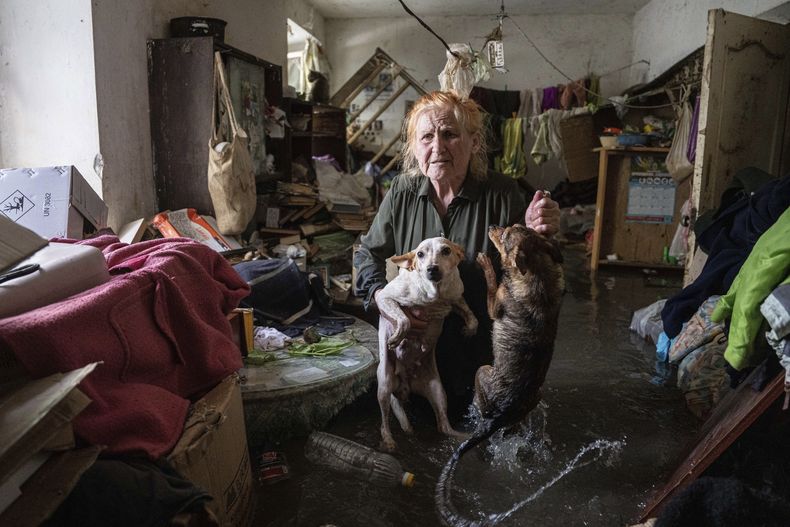 Tetiana carga a sus mascotas, Tsatsa and Chunya, parada al interior de su casa que se inundó cuando la represa Kakhovka estalló durante la noche en Jersón, Ucrania, el martes 6 de junio de 2023. (AP Foto/Evgeniy Maloletka)