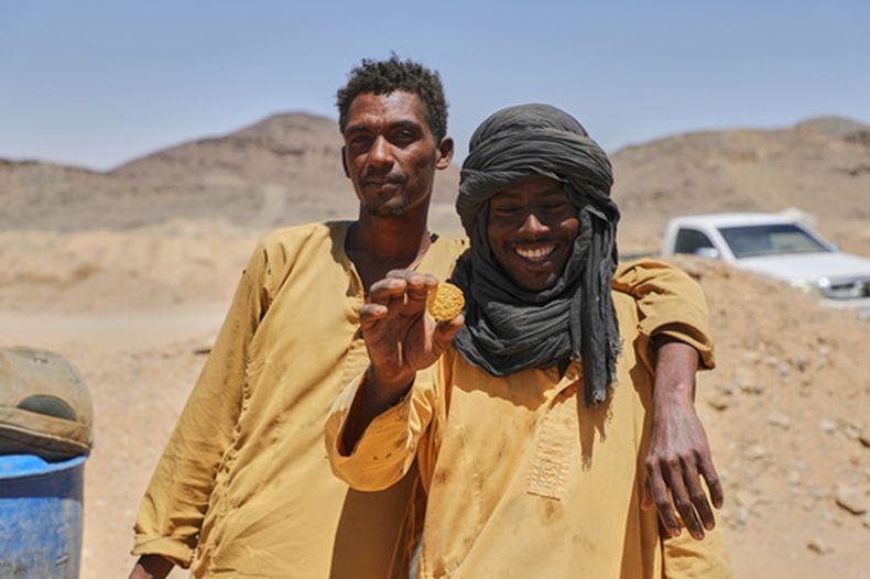 El minero Atta al-Khazin, a la derecha, muestra un pedazo de oro producido por mineros artesanales tras procesar mineral en un yacimiento en Dalago Mahas, en el estado norteño de Sudán, el viernes 8 de mayo de 2026. (AP Foto/Mohnd Blal)
