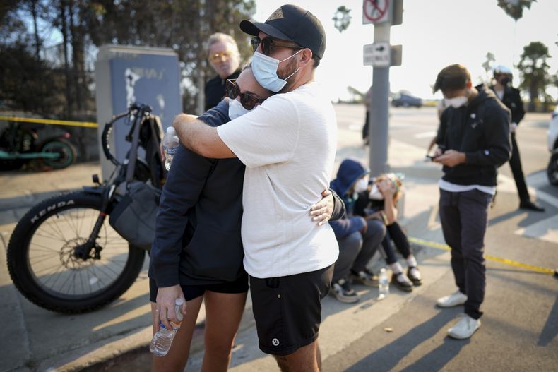 Ethan Sarani y su prometida, Hannah Simon, se abrazan mientras esperan para poder entrar a su comunidad arrasada por el fuego, en el vecindario Pacific Palisades de Los Ángeles, el 10 de enero de 2025. (AP Foto/Eric Thayer)