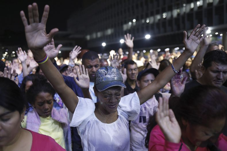 Los evangélicos levantan sus manos en oración durante un servicio al aire libre en una plaza del centro de Caracas, Venezuela, el sábado 12 de abril de 2025. (AP Foto/Cristian Hernández)