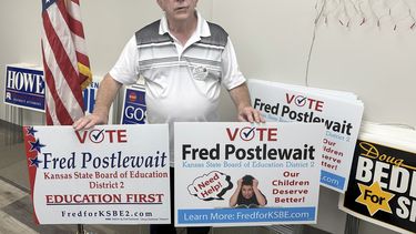 Fred Postlewait, candidato republicano a la Junta Estatal de Educación de Kansas City, Kan, muestra dos carteles disponibles para los partidarios en la sede local del Partido Republicano en el condado de Johnson, el martes 1 de octubre de 2024, en Overland Park, Kansas. (AP Foto/John Hanna)
