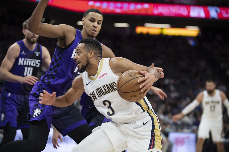 El alero de los Kings de Sacramento Keegan Murray (izquierda) marca al armador de los Pelicans de Nueva Orleans CJ McCollum (3) en la segunda mitad del juego de baloncesto de la NBA en Sacramento, California, el domingo 7 de enero de 2024. (AP Foto/José Luis Villegas)