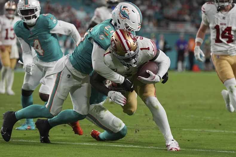 El receptor abierto de los 49ers de San Francisco, Deebo Samuel Sr. (1), es tacleado por el safety de los Dolphins de Miami, Jordan Poyer (21), justo antes de la zona de anotación durante la segunda mitad de un partido de fútbol americano de la NFL, el domingo 22 de diciembre de 2024, en Miami Gardens, Florida (AP Foto/Lynne Sladky)