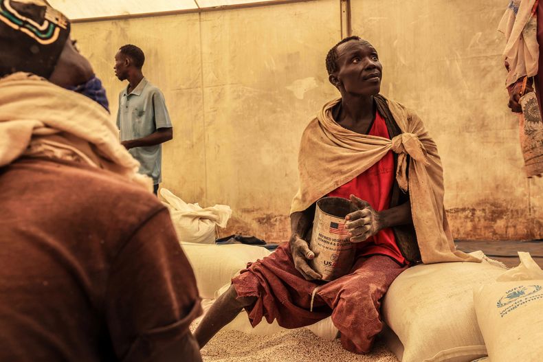 ARCHIVO - Un hombre mide las raciones de trigo que se repartirán entre las familias que esperan tras la entrega realizada por el Programa Mundial de Alimentos de Naciones Unidas en el campo de refugiados de Gendrassa, en Maban, Sudán del Sur, el 20 de agosto de 2025. (AP Foto/Caitlin Kelly, archivo)