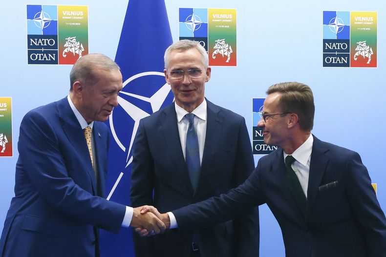El presidente turco Recep Tayyip Erdogan (i) le da la mano al primer ministro de Suecia Ulf Kristersson (d) mientras el secretario general de la OTAN Jens Stoltenberg observa, en Vilna, Lituania, el 10 de julio de 2023..(Yves Herman, Pool Photo via AP)