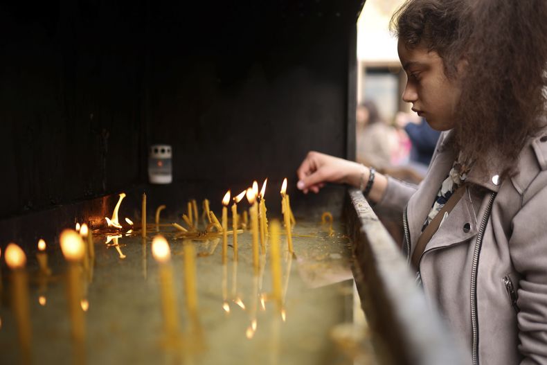 Una mujer enciende una vela frente al templo ortodoxo de San Sava, en Belgrado, Serbia, el jueves 4 de mayo de 2023. Cientos de personas se reunieron para orar por las víctimas de una masacre en una escuela, donde un niño de 13 mató a ocho estudiantes y a un guardia. (AP Foto/Armin Durgut)