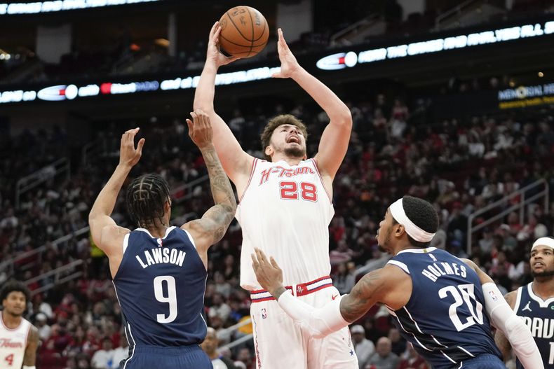 El centro de los Rockets de Houston Alperen Sengun (28) lanza sobre el armador de los Dallas Mavericks A.J. Lawson (9) y el alero Richaun Holmes durante la segunda mitad del juego de NBA el viernes 22 de diciembre de 2023, en Houston. (AP Foto/Eric Christian Smith)