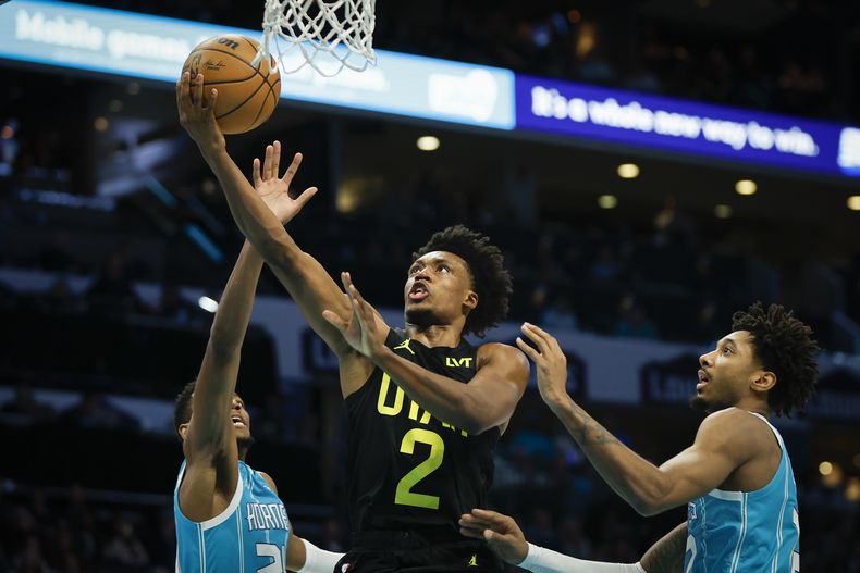 Collin Sexton, base del Jazz de Utah, salta a la cesta entre Brandon Miller (izquierda) y Leaky Black, de los Hornets de Charlotte, en el partido del sábado 27 de enero de 2024 (AP Foto/Nell Redmond)