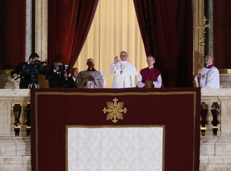 ARCHIVO - El papa Francisco, flanqueado por el monseñor Guido Marini, maestro de ceremonias litúrgicas, saluda a la multitud desde el balcón central de la basílica de San Pedro, en el Vaticano, el miércoles 13 de marzo de 2013. (AP Foto/Michael Sohn, Archivo)