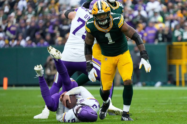 J.J. McCarthy (9), quarterback de los Vikings de Minnesota, yace en el suelo después de ser capturado por Micah Parsons (1), defensive end de los Packers de Green Bay, durante la segunda mitad de un juego de fútbol americano de la NFL el domingo 23 de noviembre de 2025, en Green Bay, Wisconsin. (AP Photo/Morry Gash)