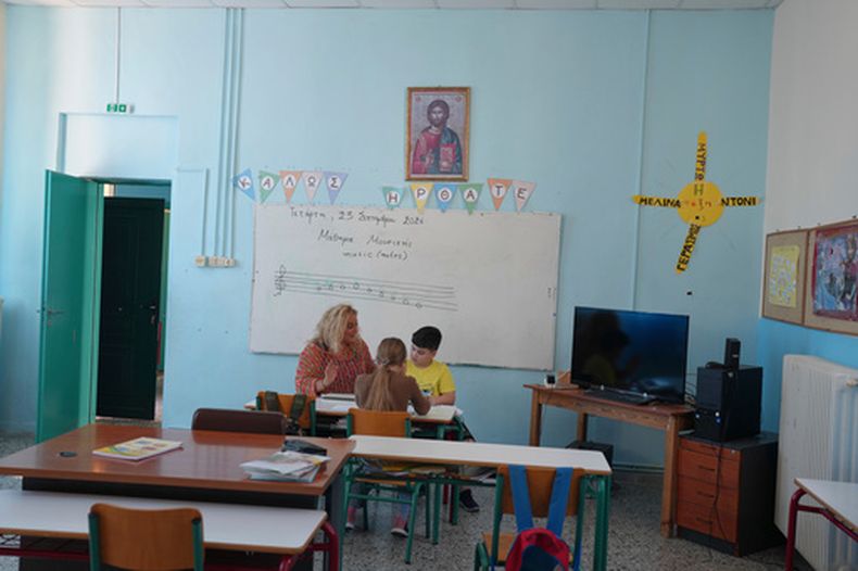 La maestra Chryssa Ntalaka enseña música a dos estudiantes de la escuela primaria Kalamos, incluido Gerasimos Mitsopoulos, de 11 años, a al derecha, en la isla de Kalamos en el mar Jónico, en el oeste de Grecia, el miércoles 23 de septiembre de 2026. (AP Foto/Petros Giannakouris)