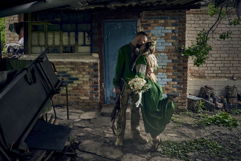 Médicos militares voluntarios, con los pseudónimos Nikita y Polka y vestidos con atuendos nacionales, se besan durante su ceremonia de boda en su puesto en el frente en la región de Donetsk, Ucrania, el jueves 29 de junio de 2023. (AP Foto/Libkos)