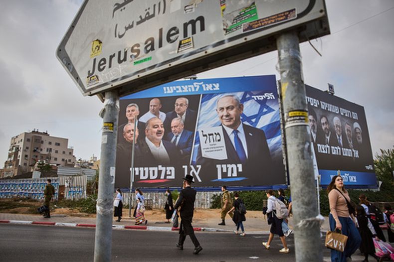 Gente camina junto a un cartel de campaña del partido Likud con la imagen del primer ministro de Israel, Benjamin Netanyahu, junto a líderes de oposición, con el lema en hebreo Derecha o Palestina antes de las elecciones generales de Israel, en Beni Brak, Israel, el domingo 25 de octubre de 2026. (AP Foto/Oded Balilty)