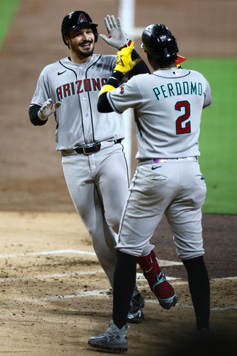 Nolan Arenado, izquierda, de los Diamondbacks de Arizona, celebra con Geraldo Perdomo (2) después de bataer un cuadrangular de dos carrers en la tercera entrada del juego de béisbol de Grandes Ligas ante los Padres de San Diego, el viernes 25 de septiembre de 2026, en San Diego. (AP Foto/Karl Anderson)