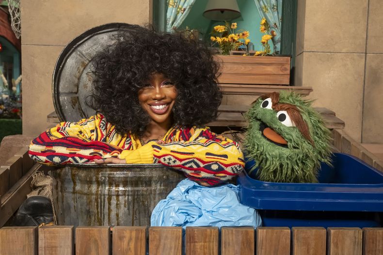 Esta imagen proporcionada por Sesame Workshop muestra al cantante SZA, a la izquierda, con el personaje de los muppets Oscar the Grouch en el set de Sesame Street. (Richard Termine/Sesame Workshop via AP)