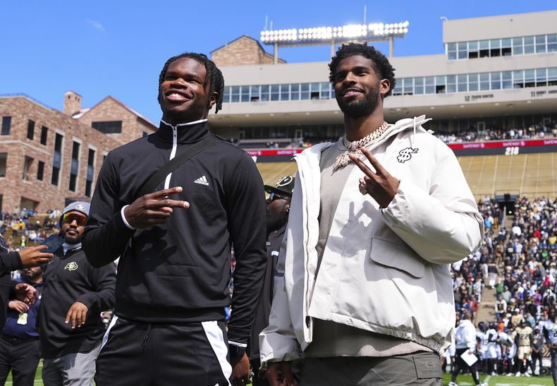 Travis Hunter, izquierda, y Shedeur Sanders, derecha, reaccionan después de que la Universidad de Colorado retiró sus jerseys durante un partido de fútbol americano de primavera, el sábado 19 de abril de 2025, en Boulder, Colorado. (AP Foto/Jack Dempsey)