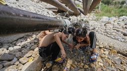 Niños tratan de refrescarse con agua que sale de un ducto en medio del calor en Jammu, India, el 10 de junio del 2025. (AP foto/Channi Anand)