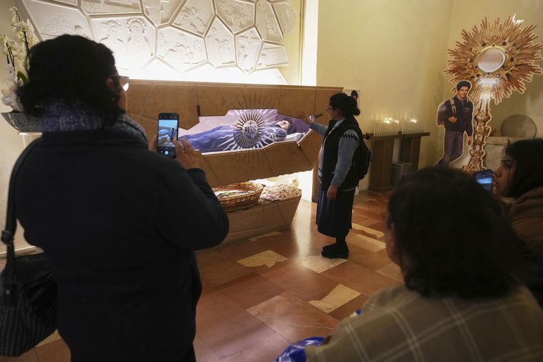 Fieles oran frente al cuerpo de Carlo Acutis, un adolescente italiano que murió de leucemia en 2006, cuando sólo tenía 15 años, y beatificado en 2020, en la iglesia de Santa María la Mayor en Asís, Italia, el miércoles 2 de abril de 2025. (AP Foto/Alessandra Tarantino)