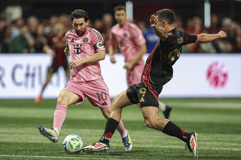 El delantero de Inter Miami Lionel Messi (10) lucha por el balón contra el mediocampista del Atlanta United Bartosz Slisz (derecha), durante la primera mitad de un partido de la MLS, el domingo 16 de marzo de 2025, en Atlanta. (AP Foto/Colin Hubbard)