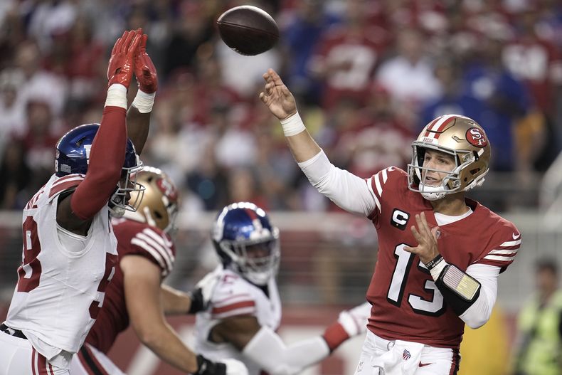 El quarterback Brock Purdy (13), de los 49ers de San Francisco, lanza el balón ante la presión del linebacker de los Giants de Nueva York, Bobby Okereke, durante la segunda mitad del partido de la NFL, en Santa Clara, California, el jueves 21 de septiembre de 2023. (AP Foto/Godofredo A. Vásquez)