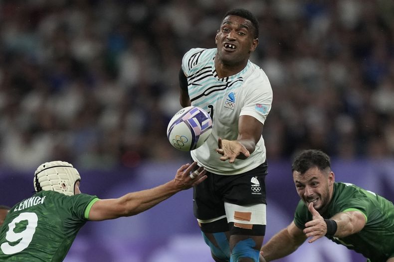 El fiyiano Joji Nasova pasa el balón ante el irlandés Hugo Lenox en los cuartos de final del torneo de rugby sevens de los Juegos Olímpicos de París, el jueves 25 de julio de 2024, en Saint-Denis, Francia. (AP Foto/Tsvangirayi Mukwazhi)