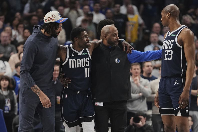 Kyrie Irving (11) de los Mavericks de Dallas recibe ayuda tras sufrir una lesión en el partido contra los Kings de Sacramento, el lunes 3 de marzo de 2025. (AP Foto/Tony Gutiérrez)