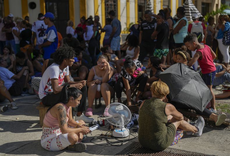 Residentes cargan sus dispositivos electrónicos en la calle durante un apagón nacional en La Habana, el sábado 15 de marzo de 2025. (AP Foto/Ramon Espinosa)