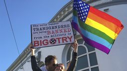 ARCHIVO - Nick Rondoletto, izquierda, y Doug Thorogood, ambos de San Francisco, ondean una bandera multicolor y sostienen un cartel durante una protesta realizada en San Francisco el miércoles 26 de julio de 2017 para oponerse a una propuesta para prohibir que personas transgénero presten servicio en el ejército de EEUU. (AP Foto/Olga R. Rodriguez, Archivo)