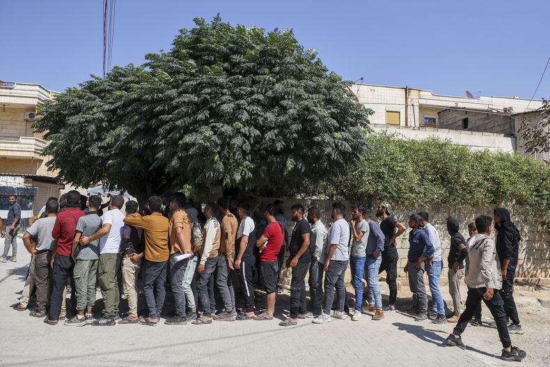 Jóvenes kurdos hacen fila para inscribirse en las fuerzas de Seguridad General del gobierno sirio en una estación de policía en Afrin, el 21 de agosto de 2025. (AP Foto/Omar Albam)
