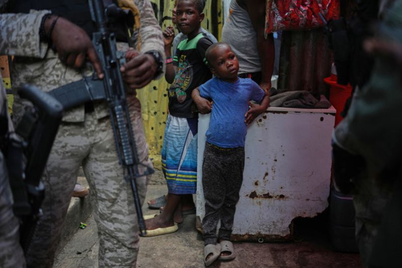 Niños al lado de policías, durante la visita de la delegada del Programa Mundial de Alimentos, la princesa Sarah Zeid de Jordania, en un refugio para familias desplazadas en Puerto Príncipe, Haití, el 27 de abril del 2026. (AP foto/Odelyn Joseph)